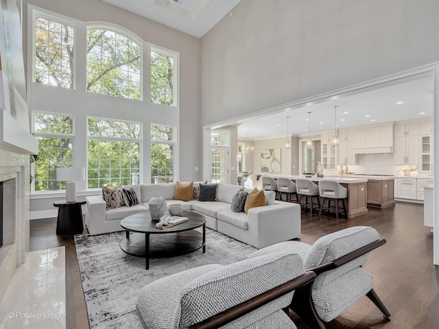 living room featuring an inviting chandelier, a high end fireplace, dark hardwood / wood-style floors, and a high ceiling