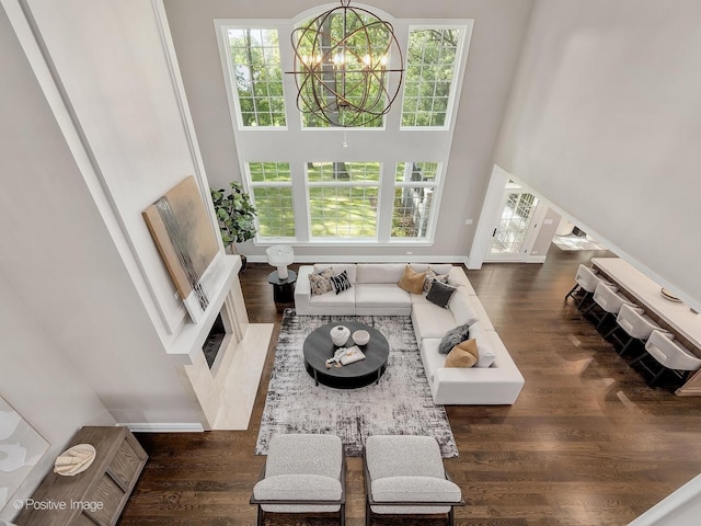 living room with a towering ceiling, dark hardwood / wood-style flooring, and a chandelier