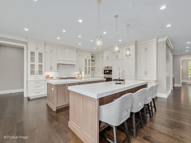 kitchen with white cabinets, hanging light fixtures, ornamental molding, a large island, and stainless steel gas cooktop