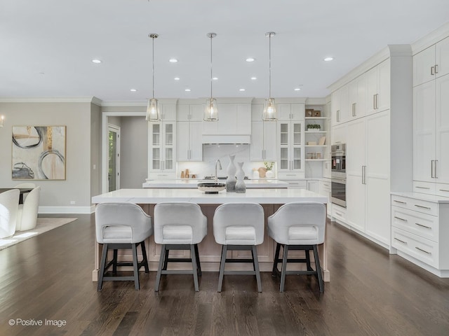 kitchen featuring white cabinetry, hanging light fixtures, sink, and a large island with sink