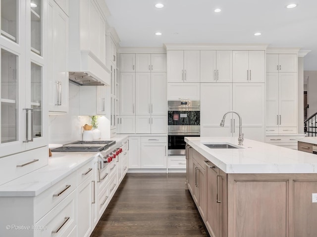 kitchen featuring sink, stainless steel appliances, light stone countertops, a kitchen island with sink, and white cabinets