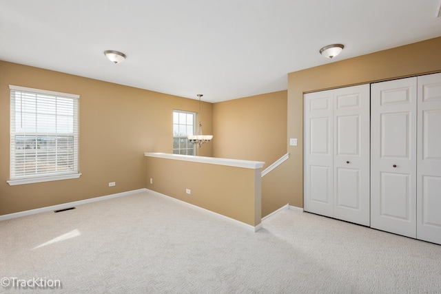 empty room with an inviting chandelier and carpet