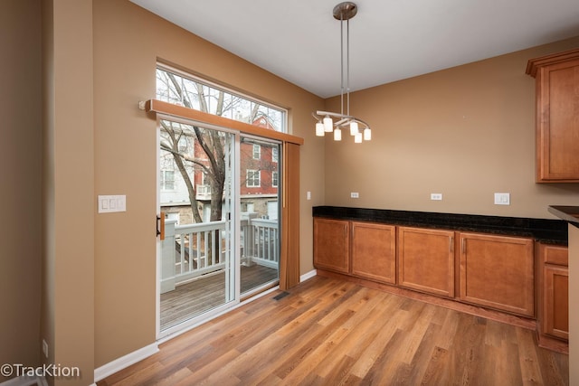 unfurnished dining area featuring a notable chandelier and light hardwood / wood-style flooring