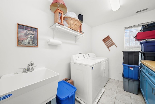 laundry area featuring separate washer and dryer, sink, and light tile patterned floors