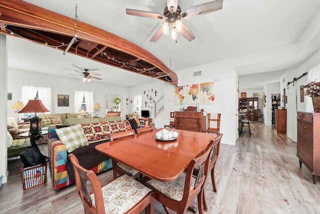 dining space featuring ceiling fan, a barn door, and light wood-type flooring