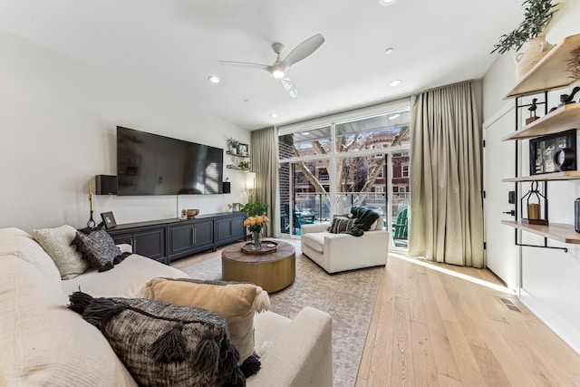 living room with recessed lighting, a ceiling fan, visible vents, light wood-style floors, and a wall of windows