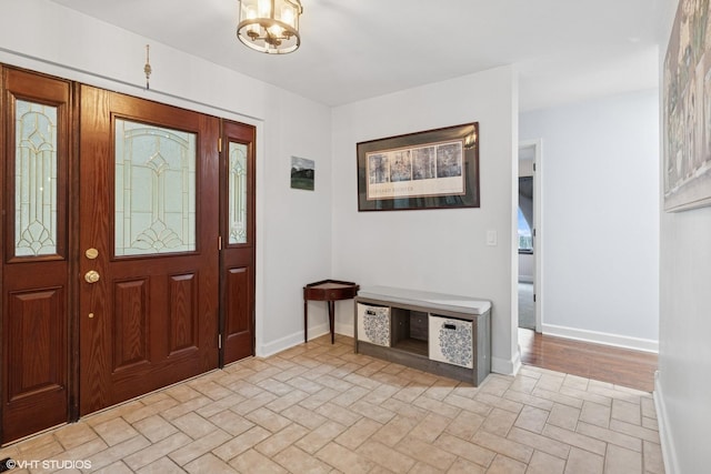 foyer entrance with brick floor, baseboards, and a chandelier