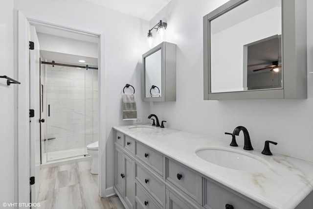 bathroom with double vanity, a sink, toilet, and a shower stall