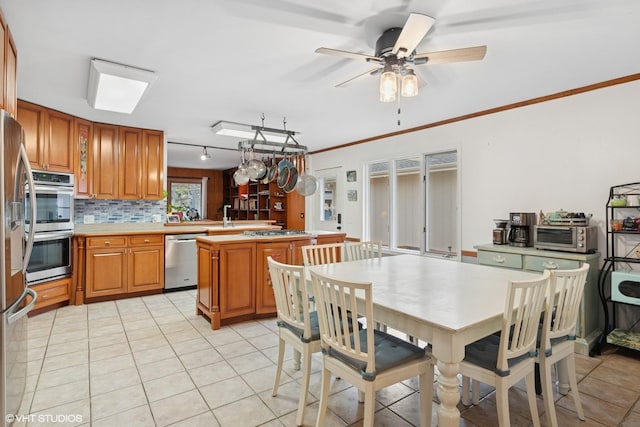 kitchen featuring crown molding, stainless steel appliances, light countertops, decorative backsplash, and a peninsula