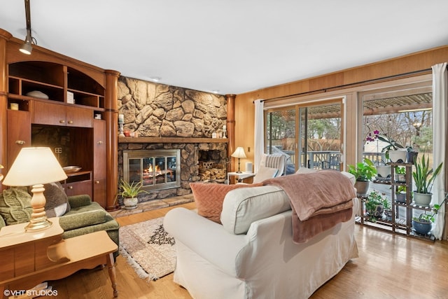 living room featuring light wood-style floors, a fireplace, and wood walls