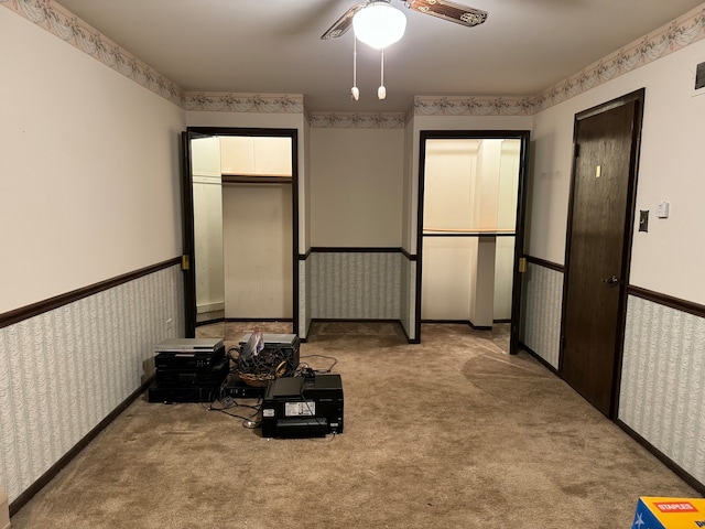 carpeted bedroom with ceiling fan and two closets