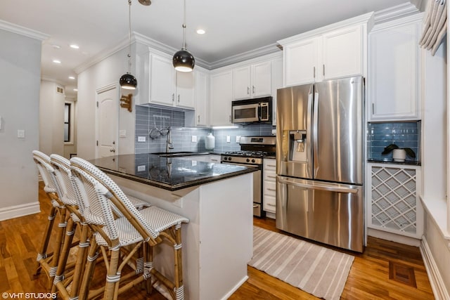 kitchen featuring sink, white cabinets, hanging light fixtures, light hardwood / wood-style floors, and stainless steel appliances