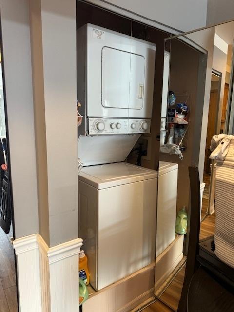 clothes washing area featuring hardwood / wood-style floors and stacked washer / dryer