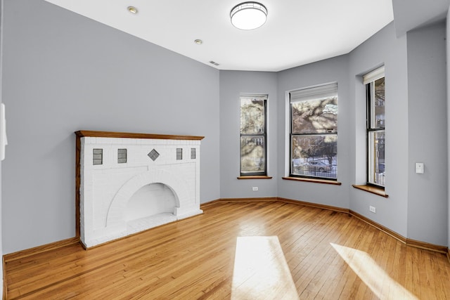 unfurnished living room featuring a fireplace and light hardwood / wood-style flooring