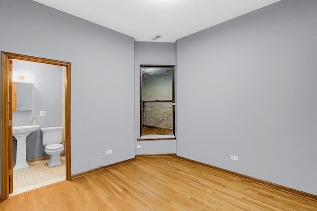 unfurnished bedroom with connected bathroom and light hardwood / wood-style flooring