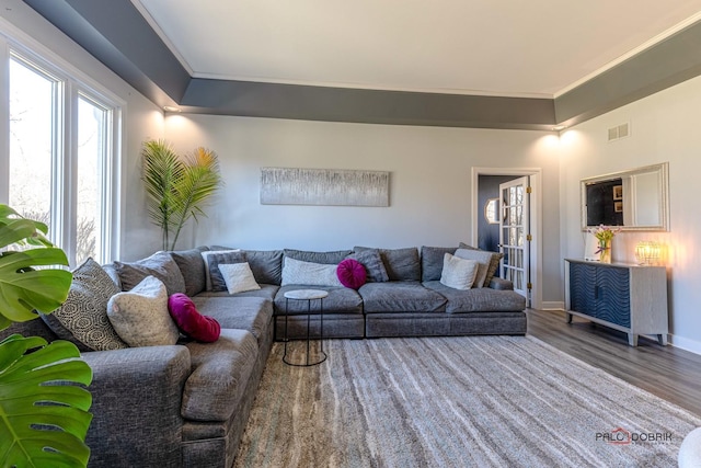 living room featuring visible vents, crown molding, baseboards, and wood finished floors