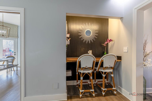 dining room featuring a notable chandelier, wood finished floors, and baseboards