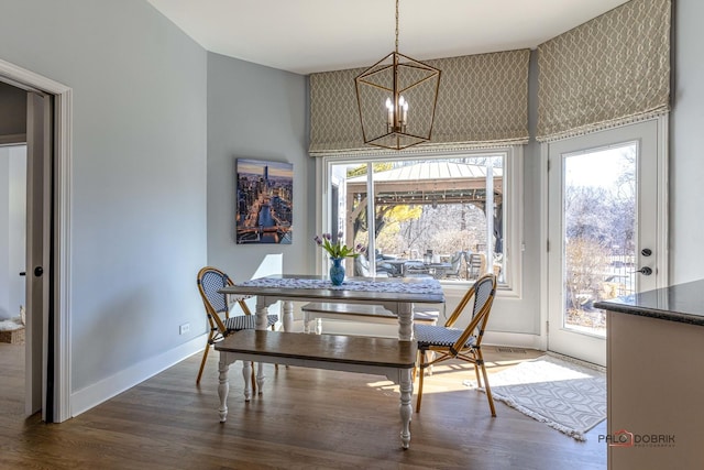 dining room featuring a notable chandelier, baseboards, and wood finished floors