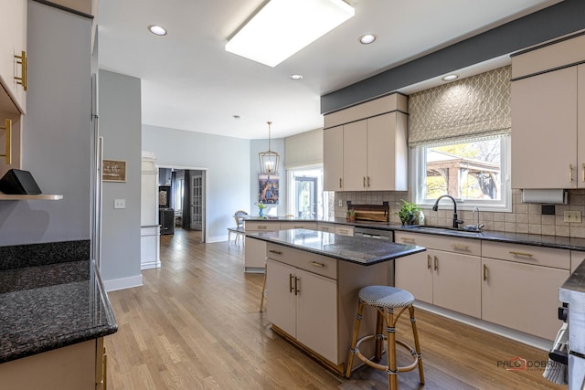 kitchen featuring a peninsula, a healthy amount of sunlight, light wood-style floors, and a sink