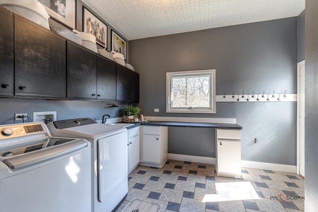 clothes washing area featuring a sink, baseboards, cabinet space, and washer and clothes dryer