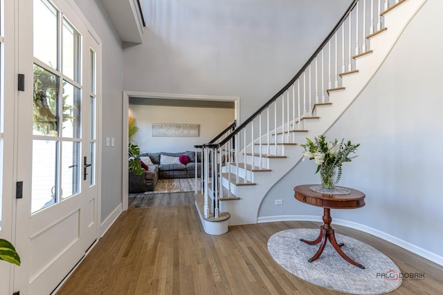 foyer entrance with baseboards, wood finished floors, and stairs