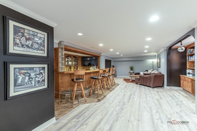 bar featuring recessed lighting, light wood-style flooring, bar area, and ornamental molding