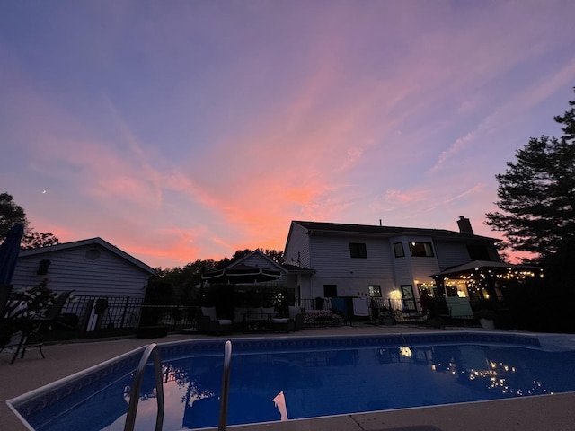 pool at dusk featuring a patio area, a fenced in pool, and fence