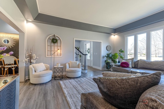 living area with stairway, baseboards, and wood finished floors