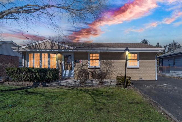 view of front of house featuring a yard, a shingled roof, crawl space, aphalt driveway, and brick siding