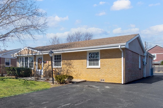 ranch-style house featuring brick siding, roof with shingles, and a front yard