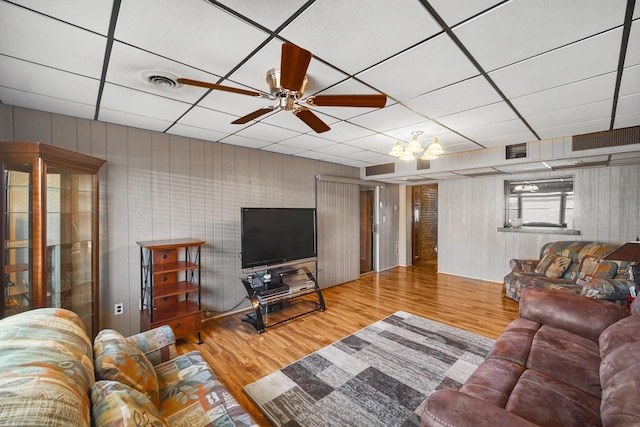 living room featuring ceiling fan, wood finished floors, visible vents, and a paneled ceiling