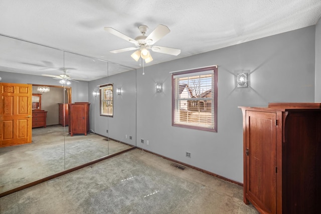 unfurnished bedroom featuring visible vents, light colored carpet, a textured ceiling, and baseboards