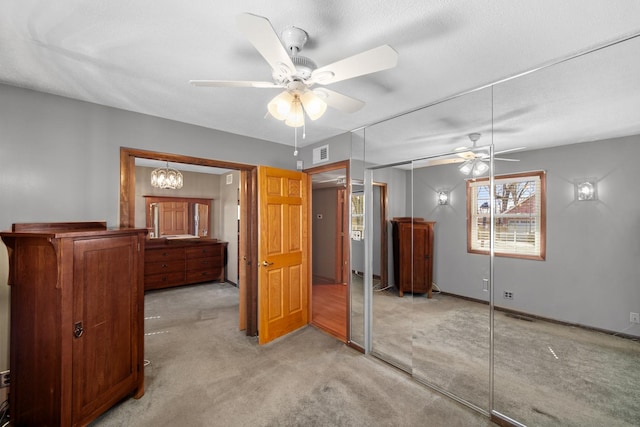 unfurnished bedroom featuring visible vents, baseboards, a closet, ceiling fan with notable chandelier, and light colored carpet