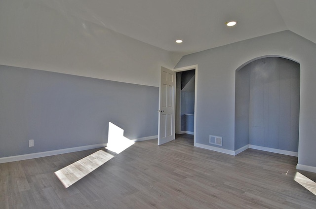 unfurnished bedroom featuring lofted ceiling and light hardwood / wood-style flooring