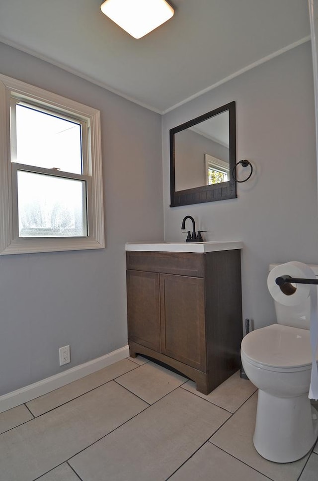 bathroom with a healthy amount of sunlight, vanity, toilet, and tile patterned flooring