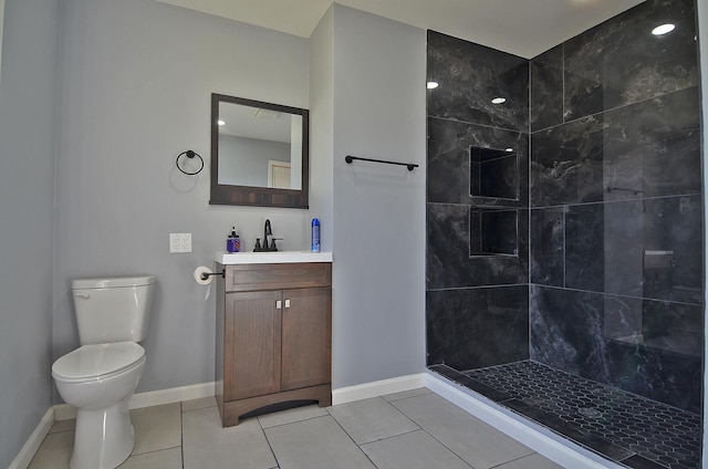 bathroom featuring tiled shower, vanity, toilet, and tile patterned flooring