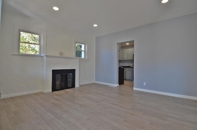 unfurnished living room featuring a fireplace and light hardwood / wood-style flooring