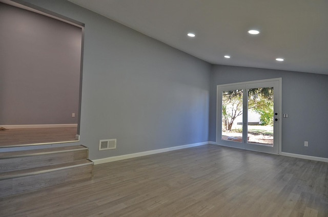 unfurnished room with lofted ceiling and hardwood / wood-style flooring