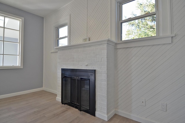 unfurnished living room with a brick fireplace and light wood-type flooring