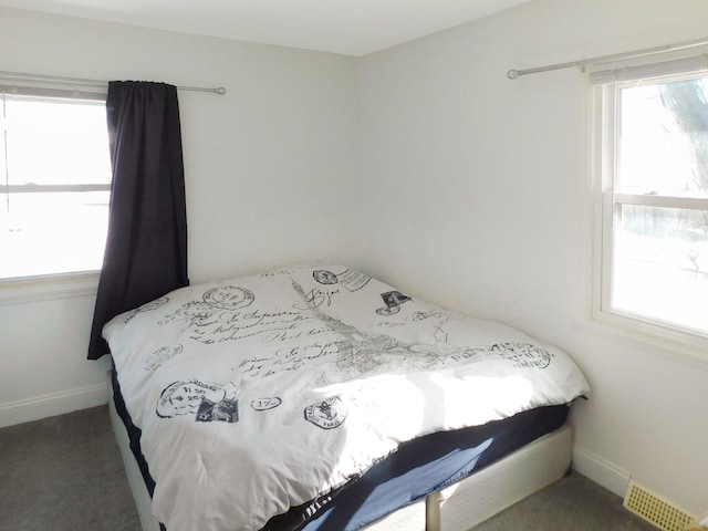 bedroom with multiple windows and dark colored carpet