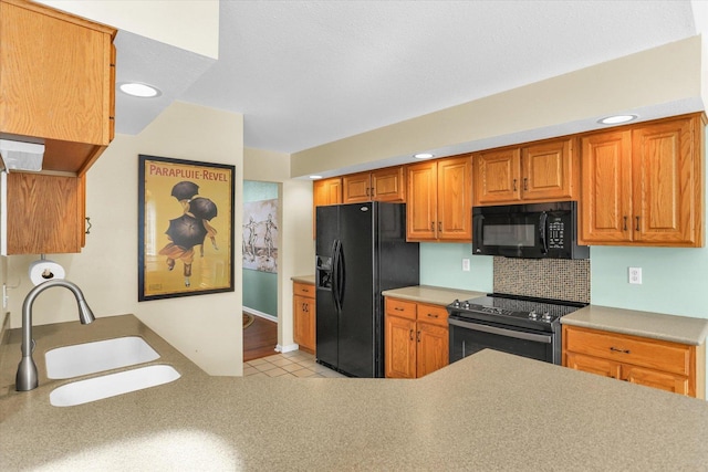 kitchen featuring black appliances, a sink, light countertops, and decorative backsplash