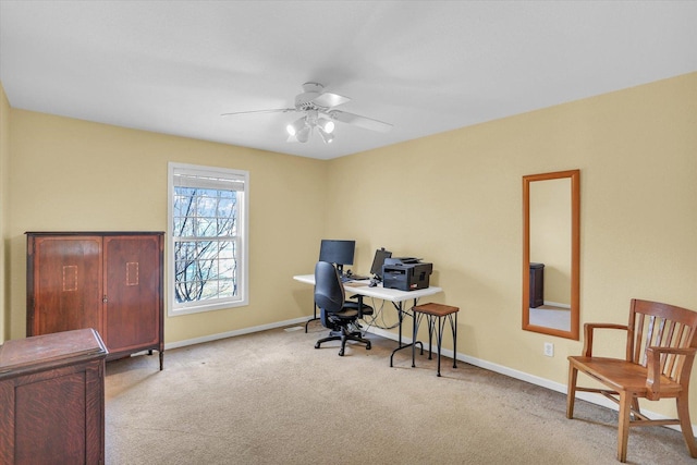 office area with a ceiling fan, light carpet, and baseboards