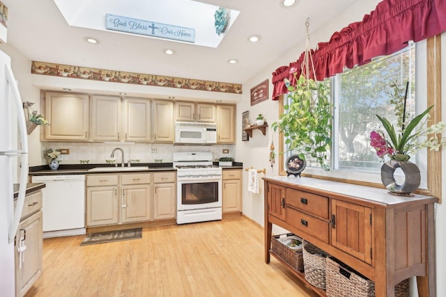 kitchen with sink, a skylight, light hardwood / wood-style flooring, white appliances, and backsplash