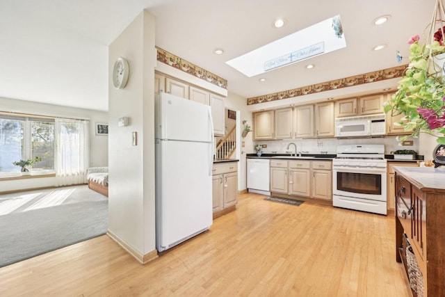 kitchen with white appliances, a skylight, light hardwood / wood-style floors, and decorative backsplash