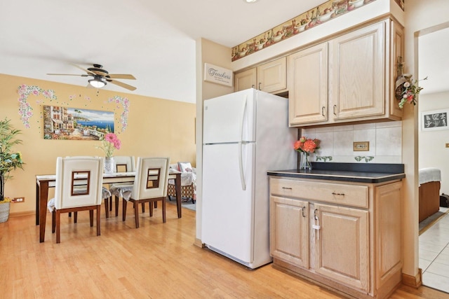 kitchen with decorative backsplash, white fridge, ceiling fan, light brown cabinets, and light wood-type flooring