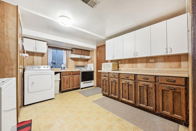 kitchen with white electric range oven, white cabinets, independent washer and dryer, and wood walls