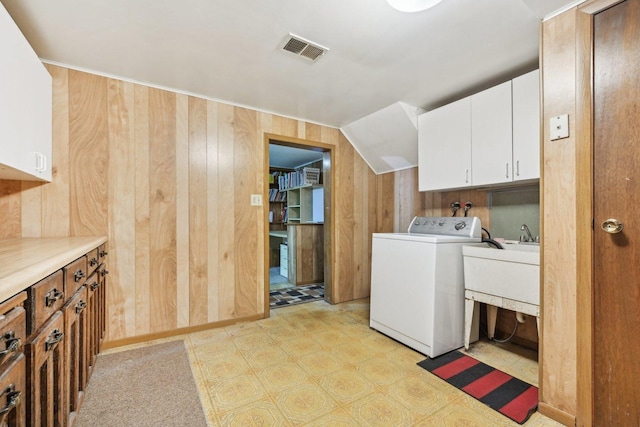 laundry area with cabinets, wooden walls, washer / dryer, and sink