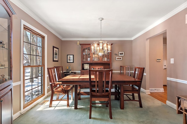 dining room with an inviting chandelier, carpet floors, and ornamental molding