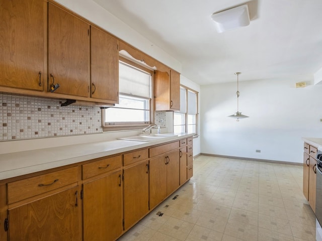 kitchen featuring brown cabinets, light countertops, a sink, and decorative light fixtures