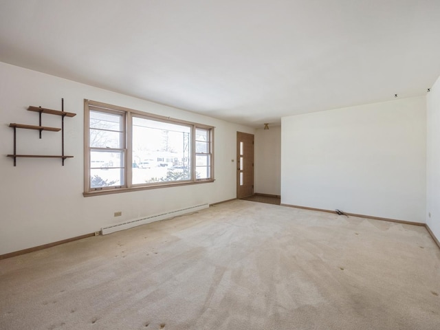 spare room featuring light carpet, baseboards, and a baseboard heating unit